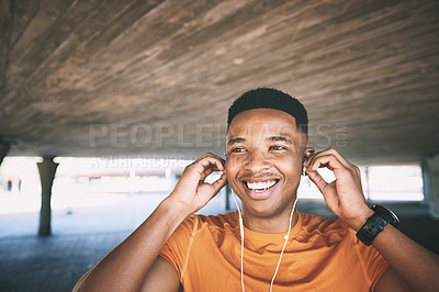 Buy stock photo Shot of a young man using earphones during his workout against an urban background