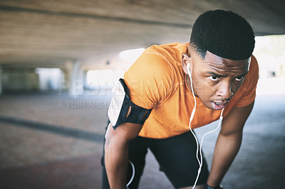 Buy stock photo Shot of a young man taking a break after working out against an urban background