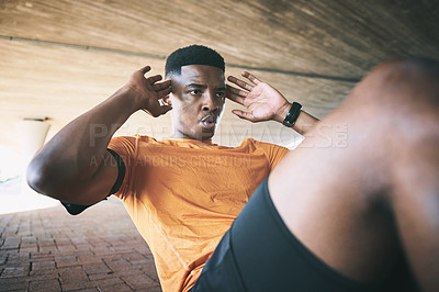 Buy stock photo Shot of a young man doing sit ups against an urban background
