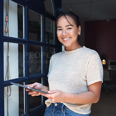 Buy stock photo Cropped portrait of an attractive young business owner standing alone at the entrance of her studio and using a tablet
