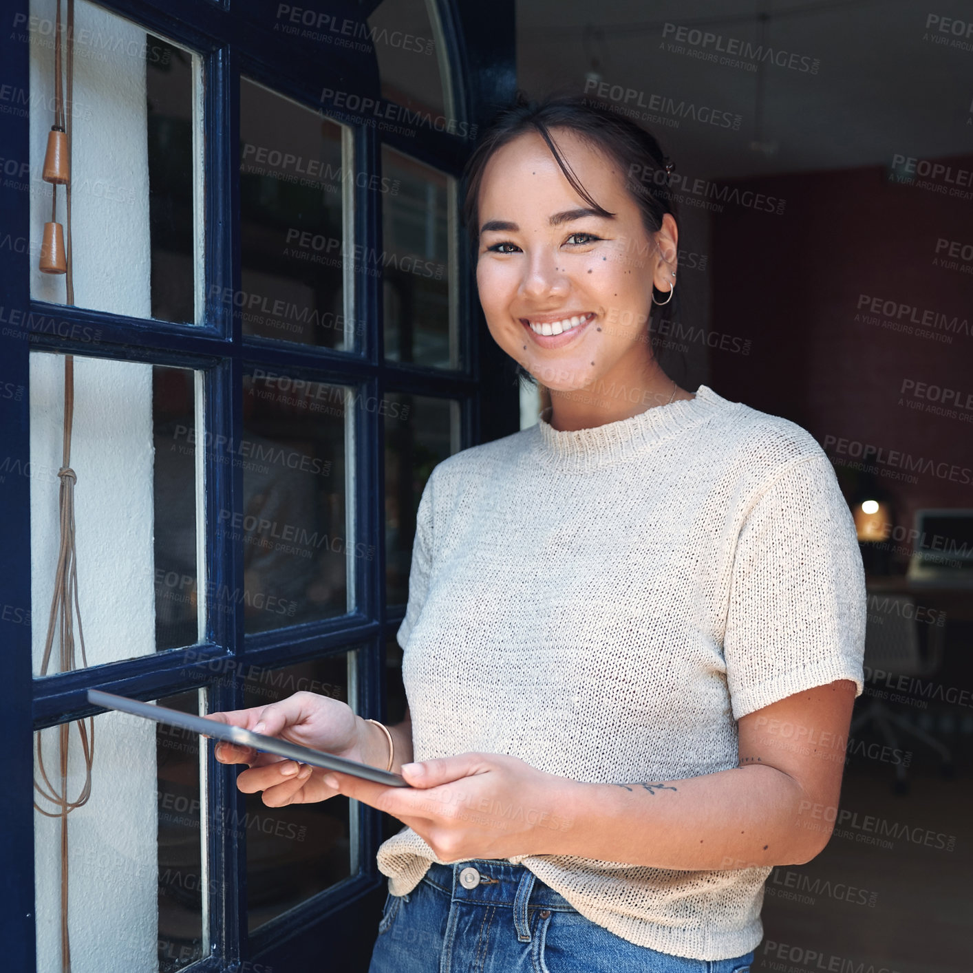 Buy stock photo Cropped portrait of an attractive young business owner standing alone at the entrance of her studio and using a tablet