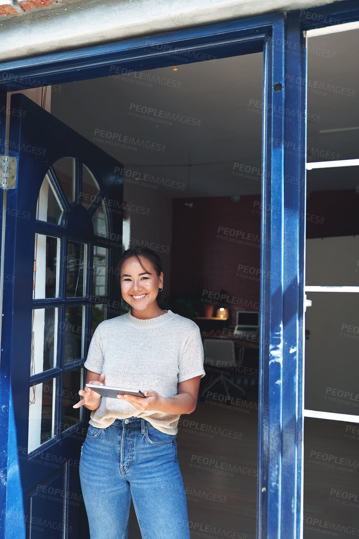 Buy stock photo Cropped portrait of an attractive young business owner standing alone at the entrance of her studio and using a tablet