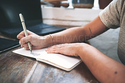 Buy stock photo Cropped shot of an unrecognizable business owner sitting alone in her pottery studio and making notes