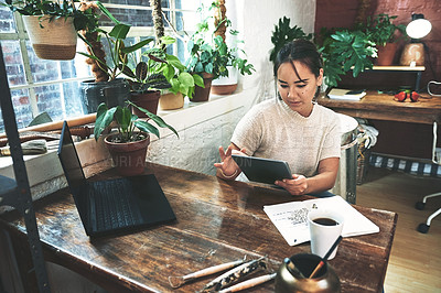 Buy stock photo Cropped shot of an attractive young business owner sitting alone in her pottery studio and using a tablet