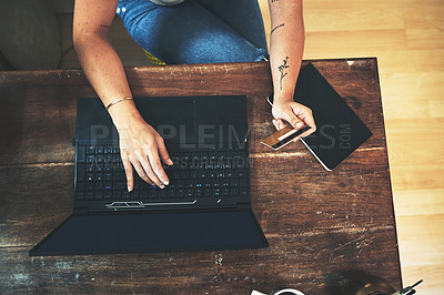 Buy stock photo High angle shot of an unrecognizable business owner sitting alone in her studio and using a laptop for online shopping