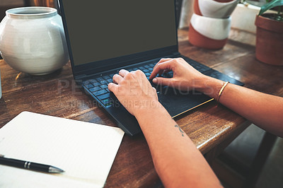 Buy stock photo Cropped shot of an unrecognizable business owner sitting alone in her pottery studio and using her laptop