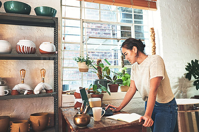 Buy stock photo Cropped shot of an attractive young business owner standing and using her laptop in her pottery studio