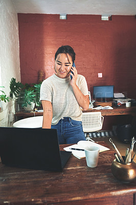 Buy stock photo Cropped shot of an attractive young business owner standing and using her laptop and cellphone in her pottery studio