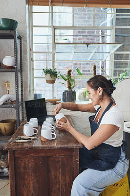 Buy stock photo Shot of a young woman making mugs in a pottery studio