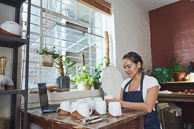 Buy stock photo Shot of a young woman making mugs in a pottery studio