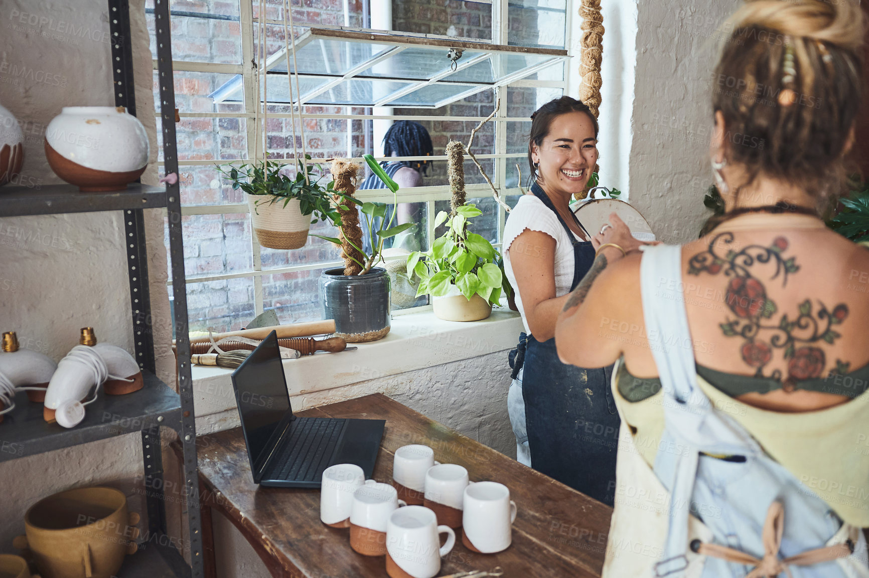 Buy stock photo Shot of two young women working together in a pottery studio