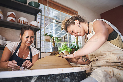 Buy stock photo Shot of two young women working with clay in a pottery studio