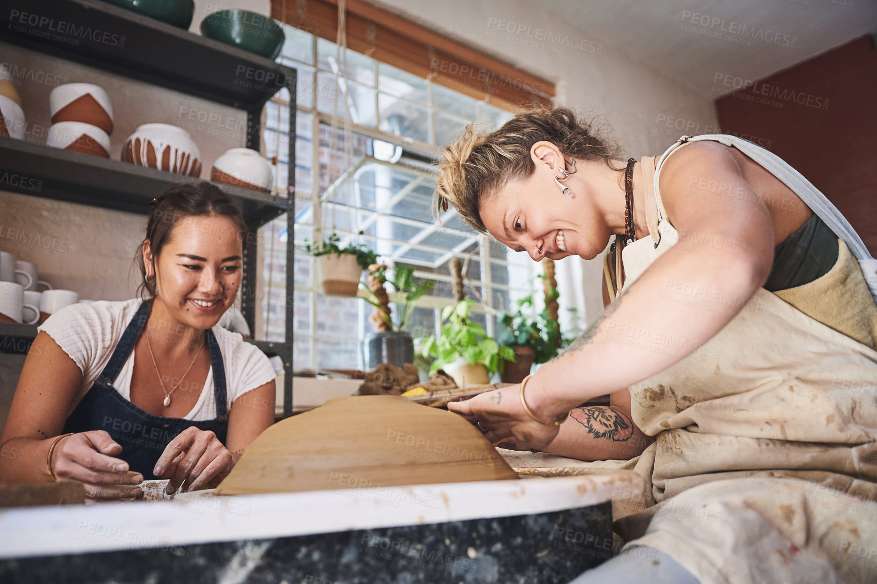 Buy stock photo Shot of two young women working with clay in a pottery studio