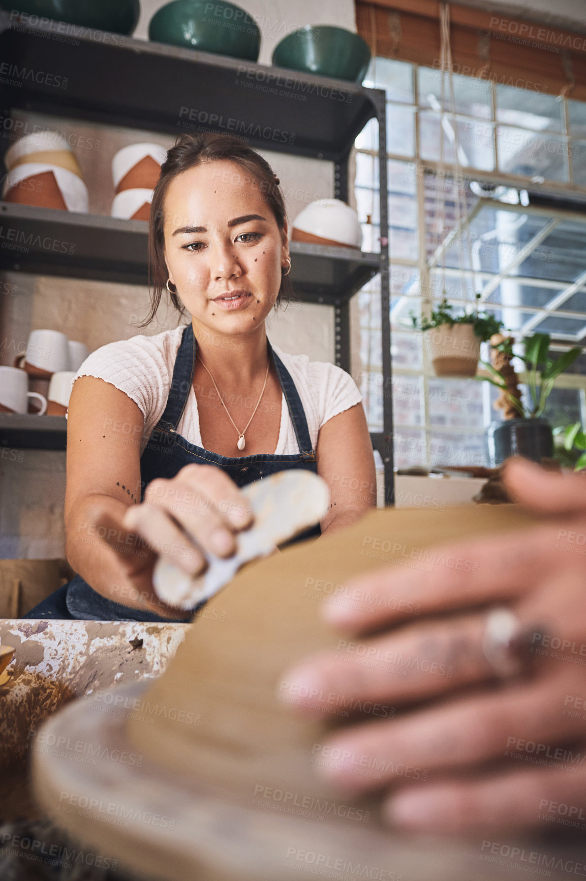 Buy stock photo Shot of two young women working with clay in a pottery studio