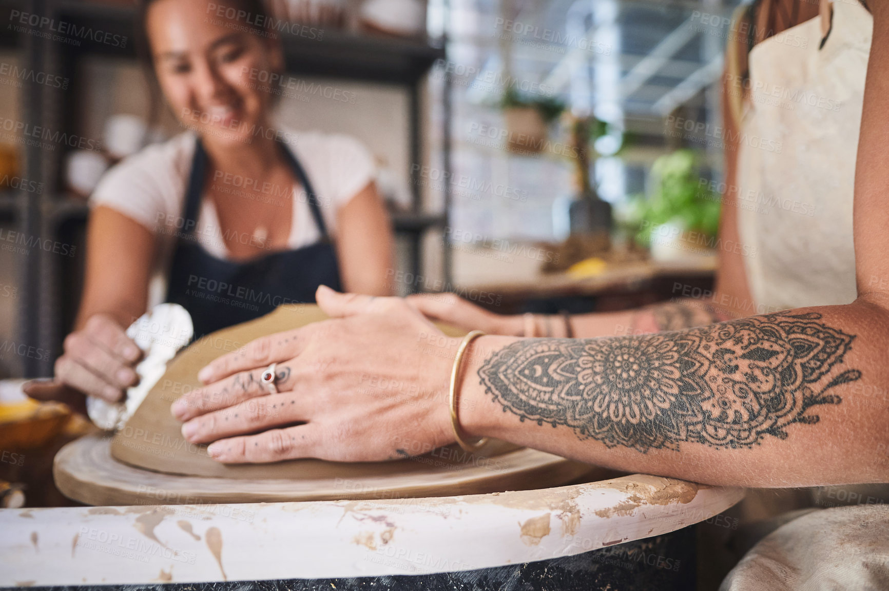 Buy stock photo Shot of two young women working with clay in a pottery studio