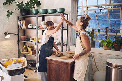 Buy stock photo Shot of two young women giving each other a high five in a pottery studio