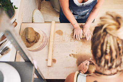 Buy stock photo Shot of two unrecognisable women kneading clay in a pottery studio