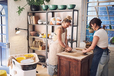 Buy stock photo Shot of two young women kneading clay in a pottery studio