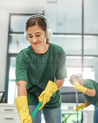 Buy stock photo Shot of a young woman cleaning an office with her colleague in the background