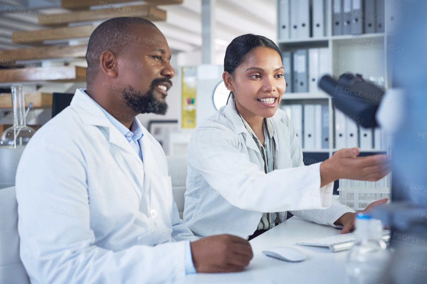 Buy stock photo Shot of two scientists working together on a computer in a lab