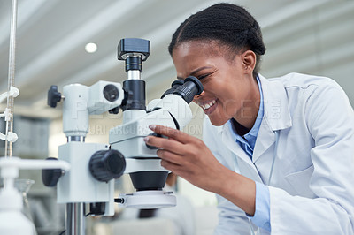 Buy stock photo Shot of a young scientist using a microscope in a lab