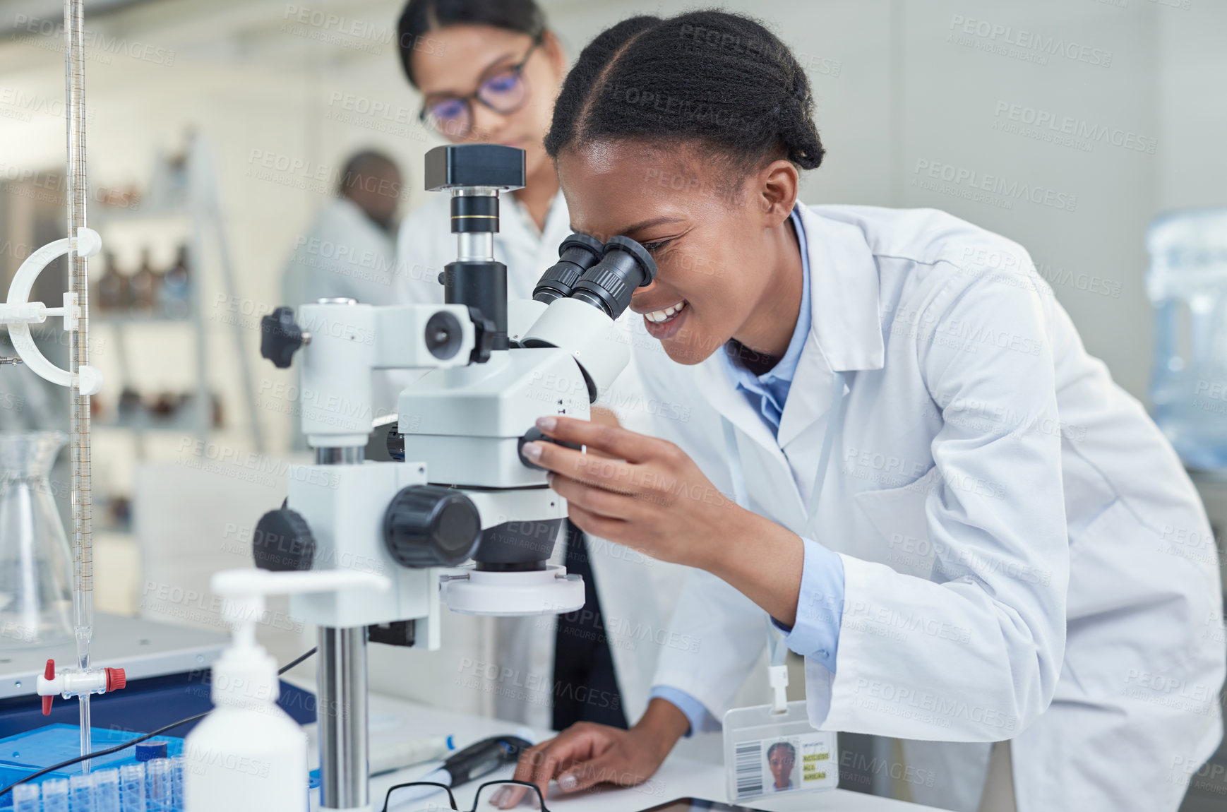 Buy stock photo Shot of a young scientist using a microscope in a lab