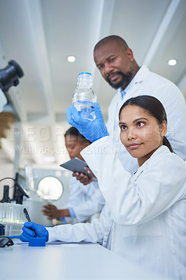 Buy stock photo Shot of a young scientist conducting research with her team in a laboratory