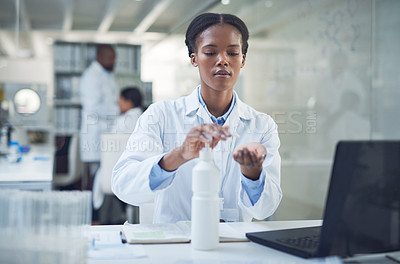 Buy stock photo Shot of a scientist disinfecting her hands while conducting research in a laboratory