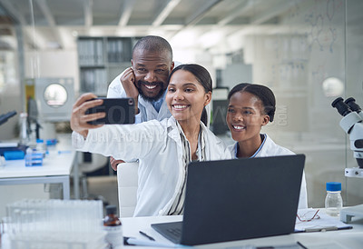 Buy stock photo Shot of a group of young scientists taking a selfie while conducting research in a laboratory