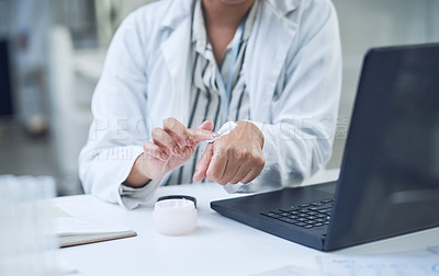 Buy stock photo Shot of a scientist applying hand cream while conducting research in a laboratory