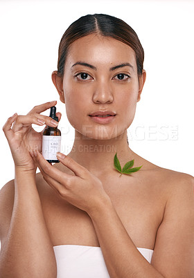 Buy stock photo Shot of a beautiful young woman holding a bottle of CBD oil against a white background
