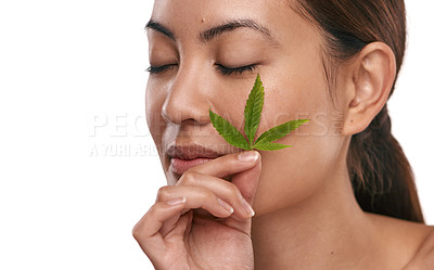 Buy stock photo Shot of a beautiful young woman holding a marijuana leaf against her face