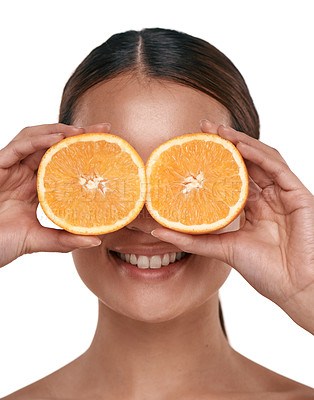 Buy stock photo Shot of a beautiful young woman holding halved oranges over her eyes