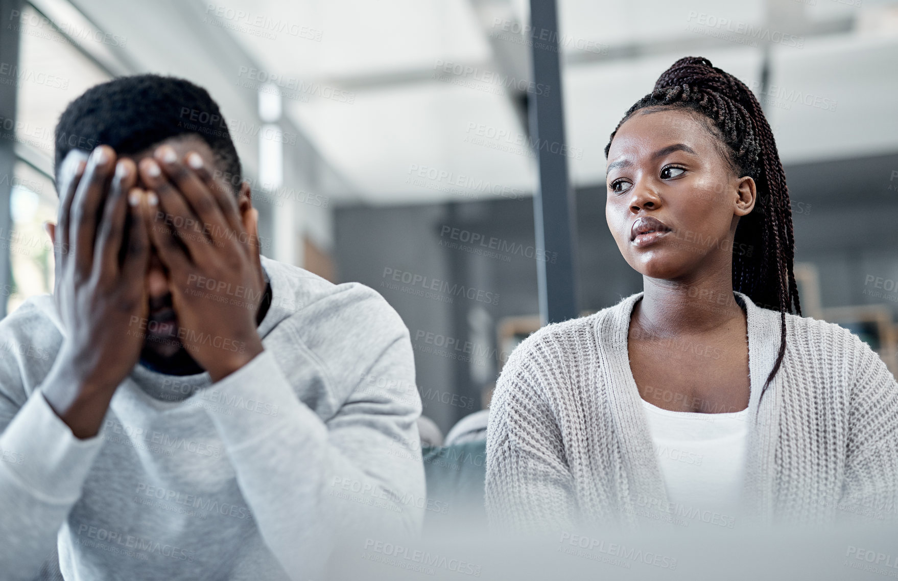 Buy stock photo Shot of a young couple ignoring each other after having an argument on the sofa at home