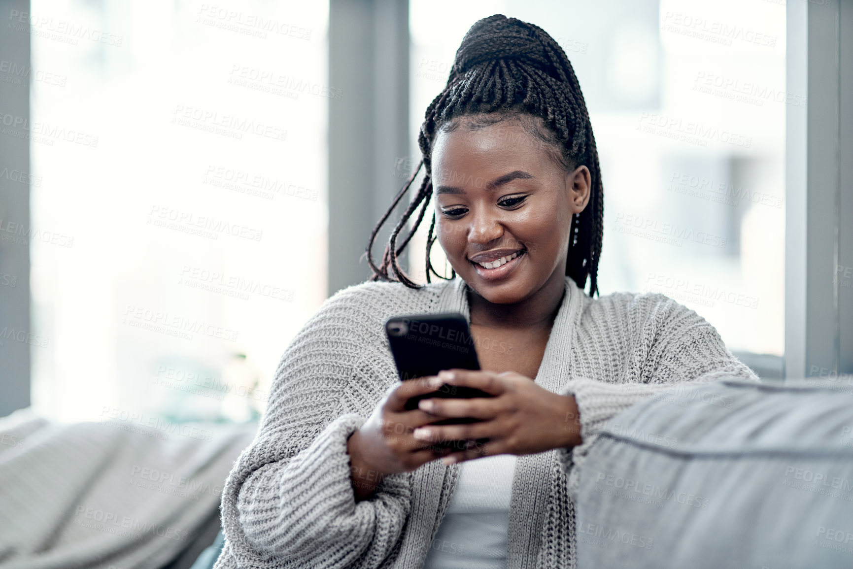 Buy stock photo Phone, relax and social media with black woman on sofa in living room of home for communication or search. App, smile and text message with happy person in apartment on weekend for internet browsing