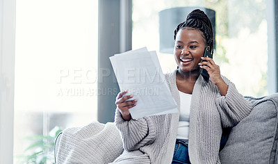 Buy stock photo Shot of a young woman going over paperwork and using a smartphone on the sofa at home