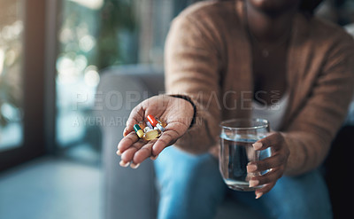 Buy stock photo Cropped shot of an unrecognizable woman sitting alone at home and holding her medication before taking them with water