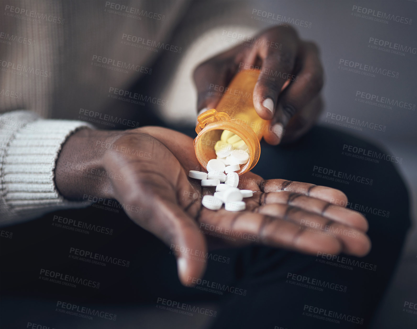 Buy stock photo Cropped shot of an unrecognizable man sitting alone and taking pills out of a pill bottle in his living room