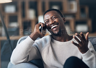 Buy stock photo Cropped shot of a handsome young man sitting alone in his living room and using his cellphone