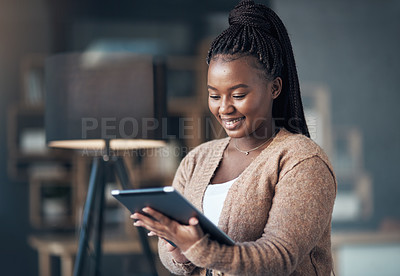 Buy stock photo Cropped shot of an attractive young woman sitting alone in her living room and using her tablet