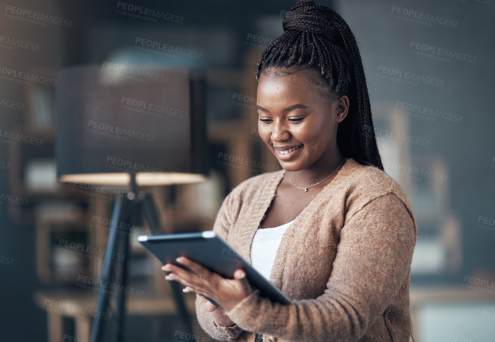 Buy stock photo Cropped shot of an attractive young woman sitting alone in her living room and using her tablet