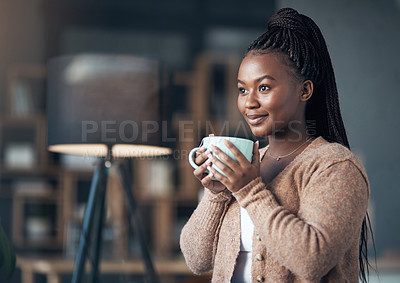 Buy stock photo Cropped shot of an attractive young woman sitting alone in her living room and enjoying a cup of coffee