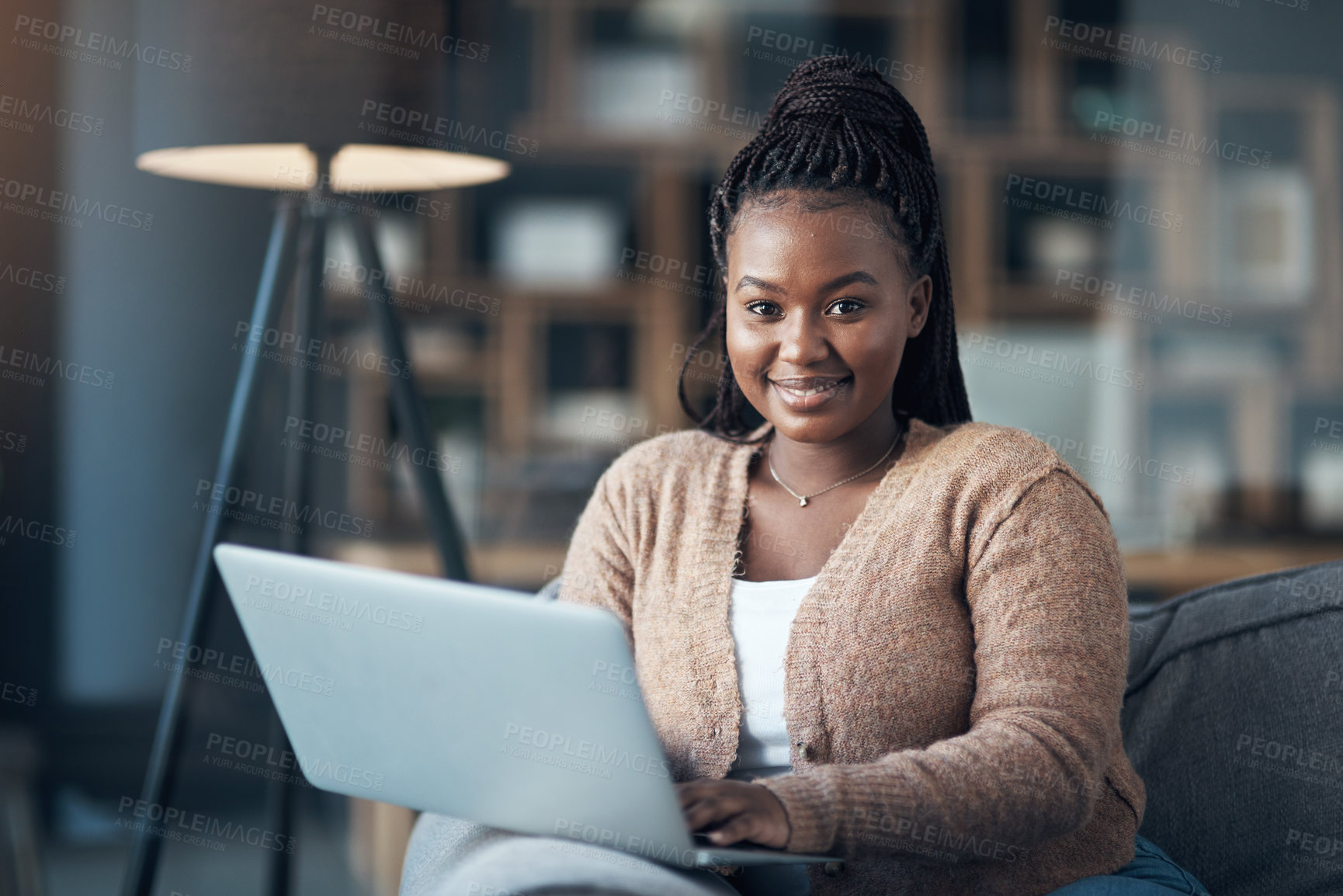 Buy stock photo Cropped shot of an attractive young woman sitting alone in her living room and using her laptop