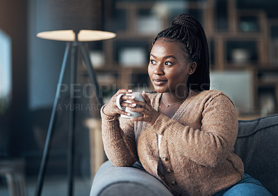 Buy stock photo Cropped shot of an attractive young woman sitting alone in her living room and enjoying a cup of coffee