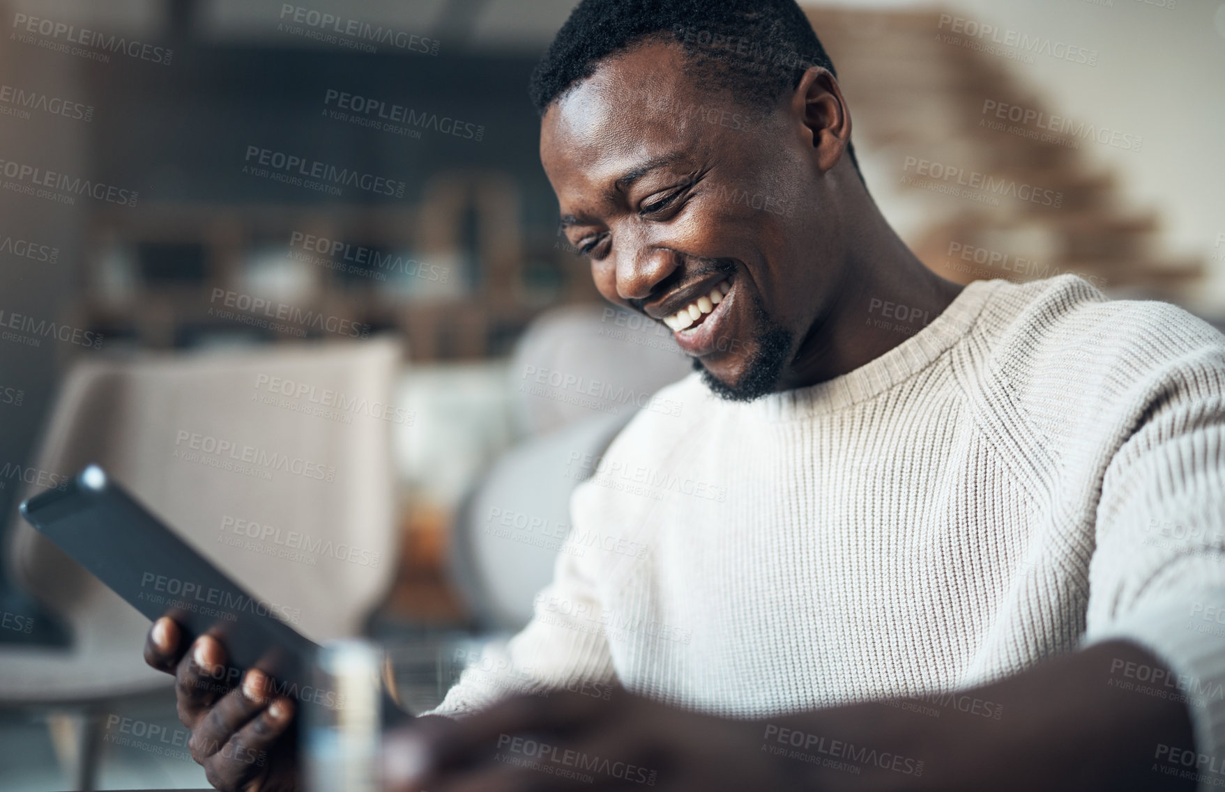 Buy stock photo Cropped shot of a handsome young man sitting alone in his living room and using his laptop