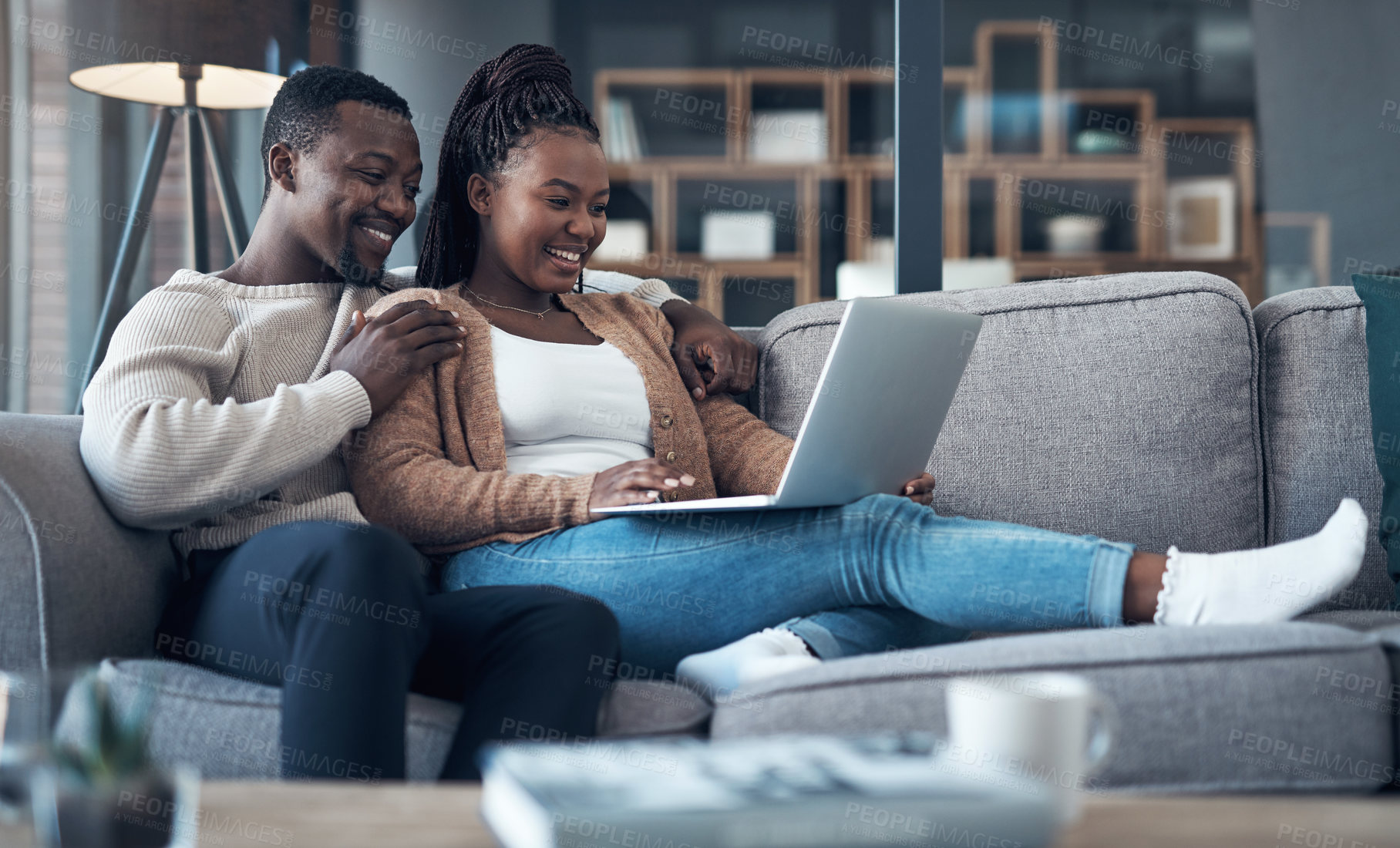 Buy stock photo Cropped shot of a happy young couple sitting together on their sofa and using a laptop for a video chat