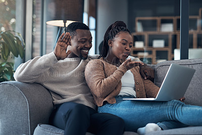 Buy stock photo Cropped shot of a happy young couple sitting together on their sofa and using a laptop for a video chat