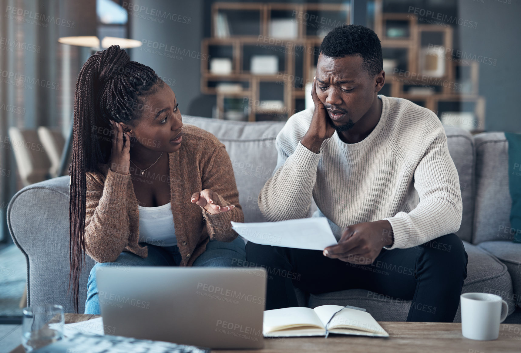 Buy stock photo Cropped shot of a young couple sitting on the sofa together and using a laptop while going through their finances