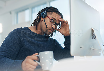 Buy stock photo Shot of a young businessman wearing a headset and looking stressed out while working on a computer in an office