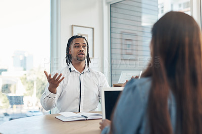 Buy stock photo Shot of a young businessman having a discussion with a colleague in an office